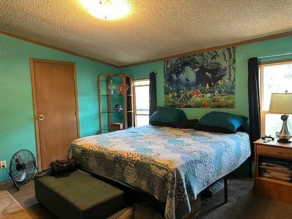 a bedroom with a bed and dresser with wooden floor