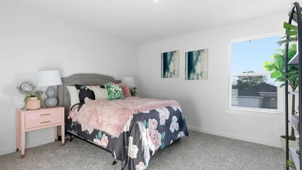 a bedroom with a bed lamp and a potted plant