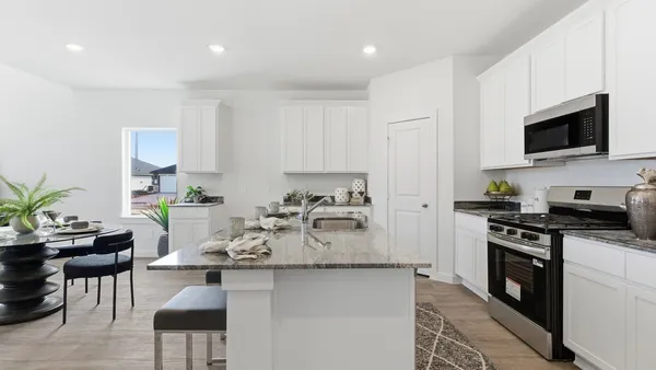 a kitchen with stainless steel appliances granite countertop a stove top oven a sink a dining table and chairs