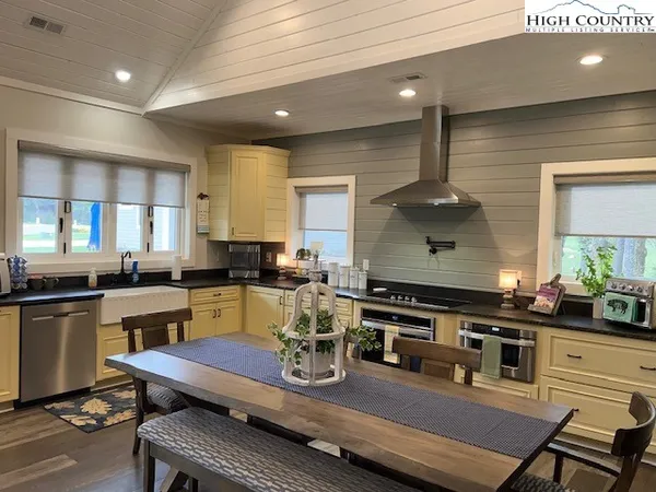 a kitchen with stainless steel appliances kitchen island granite countertop a table chairs in it and wooden floors