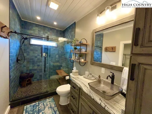 a bathroom with a granite countertop sink a toilet a mirror and shower