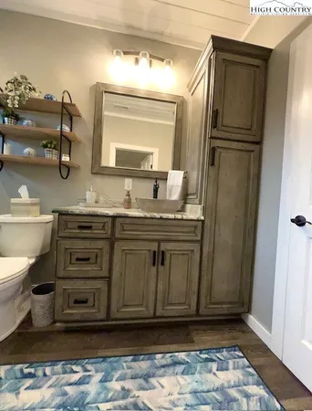 a bathroom with a granite countertop sink toilet and mirror