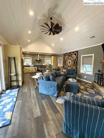 a living room with furniture kitchen view and a wooden floor