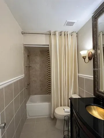a bathroom with a granite countertop bathtub sink vanity mirror and toilet