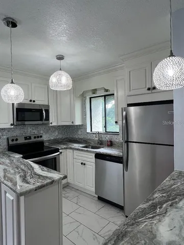 a kitchen with granite countertop a sink a counter and stainless steel appliances