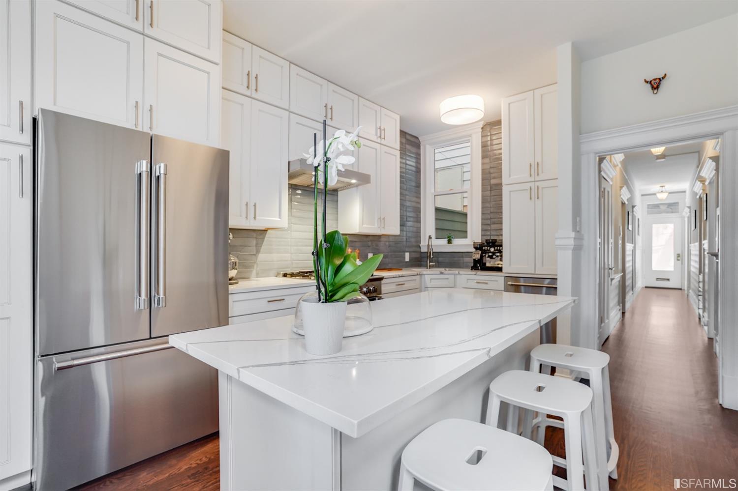 a kitchen with stainless steel appliances a refrigerator a sink and white cabinets