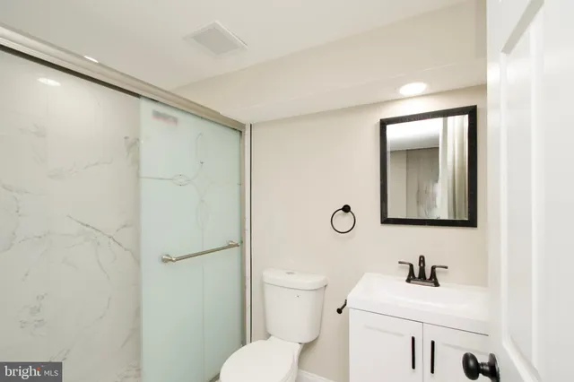 a bathroom with a toilet sink vanity and mirror