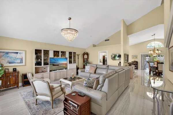 a living room with furniture a chandelier couches and a dining table with a large window