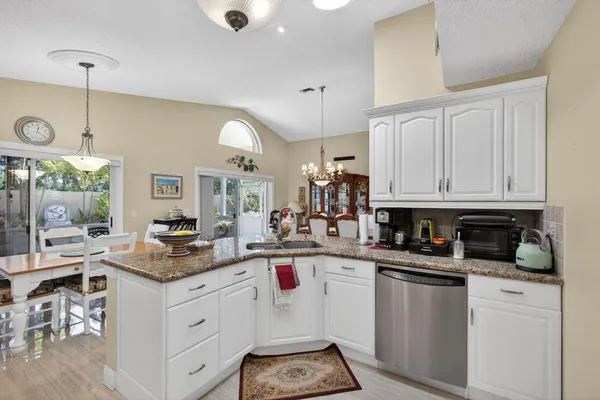 a kitchen with granite countertop white cabinets and stainless steel appliances