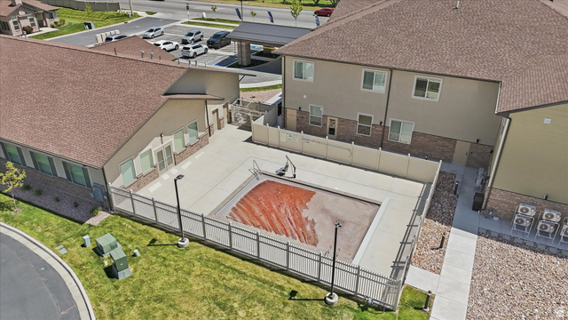 1838 West 300th Street South, Unit B Mapleton, UT 84664 - Photo 50 of 51 Fenced outdoor pool area with surrounding concrete decking, bordered by a multi-story building featuring tan siding and brick accents