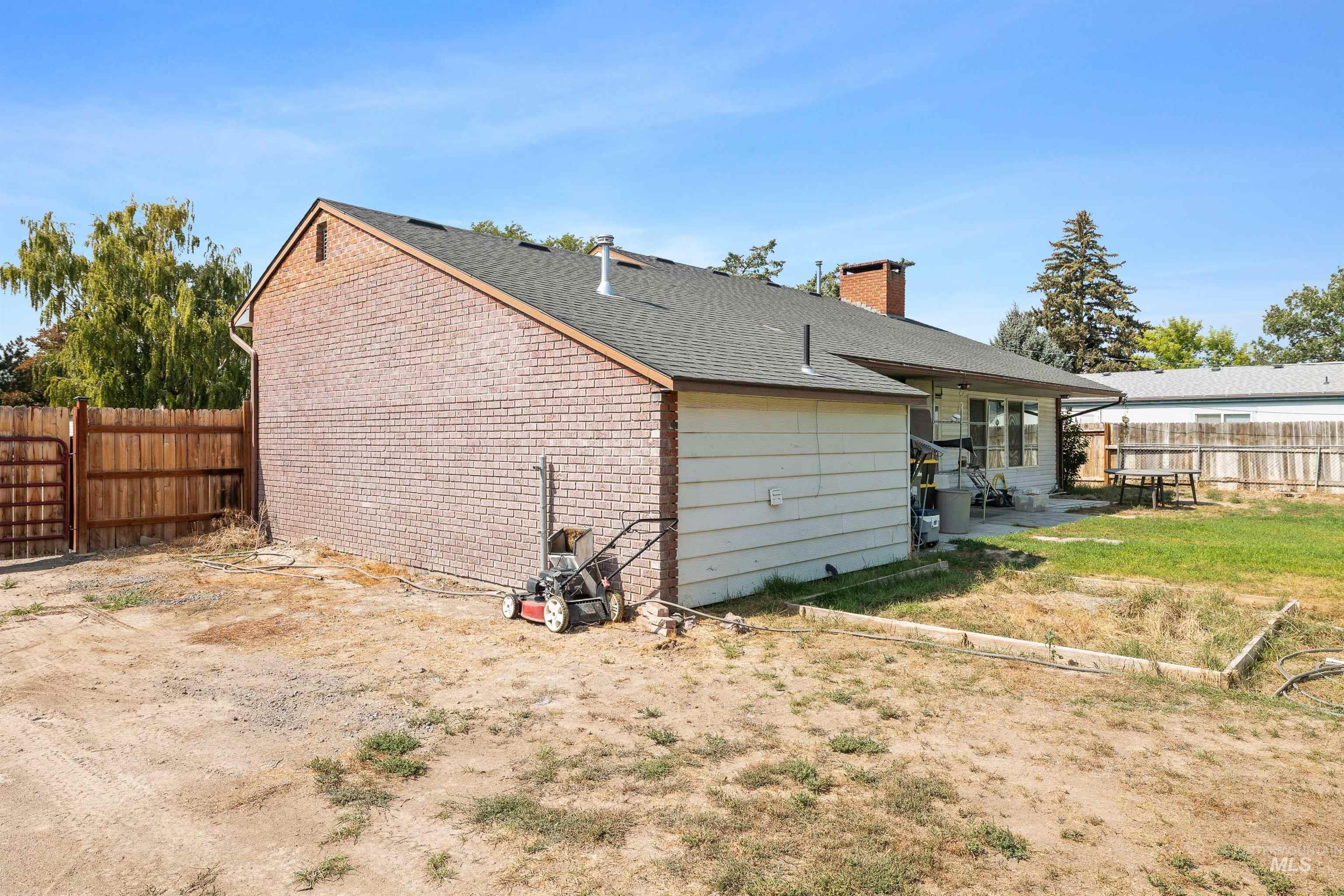 817 Union Avenue Filer, ID 83328 - Photo 27 of 37 Rear view of house featuring a fenced backyard, roof with shingles, a chimney, and a patio area