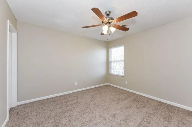 an empty room with a window and a fan