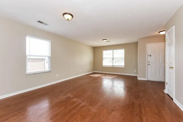 a view of an empty room with wooden floor and a window