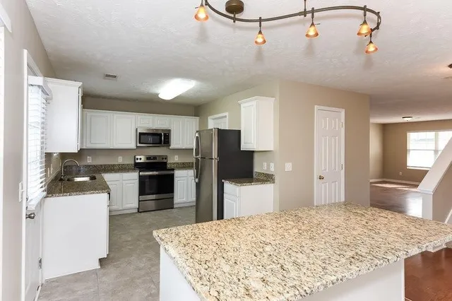 a kitchen with kitchen island a refrigerator sink stove and oven