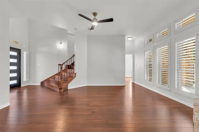 a view of an empty room with a window and wooden floor