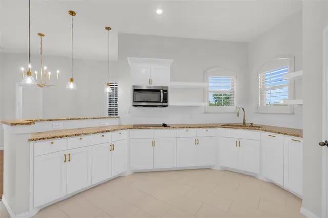 a large white kitchen with granite countertop a sink and white cabinets