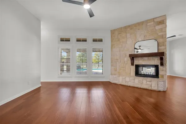 a view of an empty room with wooden floor fireplace and a window