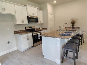 235 Bittern Loop Inverness, FL 34453 - Photo 2 of 10 a kitchen with stainless steel appliances granite countertop a stove a sink dishwasher and a microwave oven with white cabinets