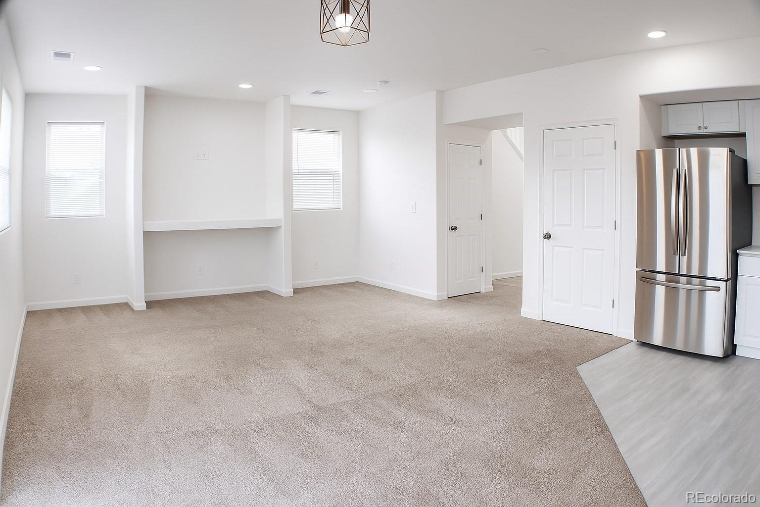 3583 East Uintah Street, Unit 102 Colorado Springs, CO 80909 - Photo 4 of 23 a view of an empty room with wooden floor and a kitchen