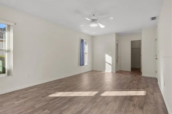 a view of an empty room with wooden floor and a window