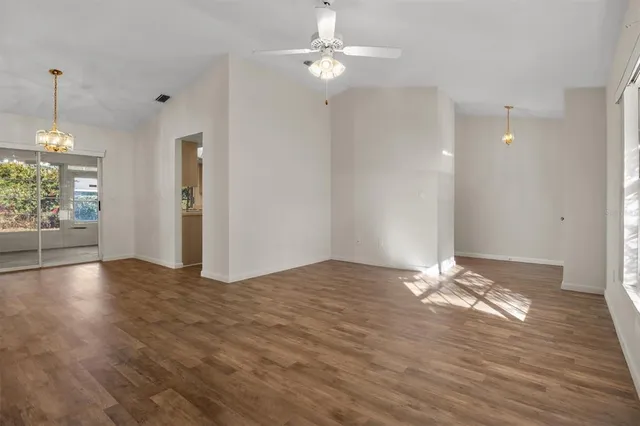 a view of empty room with wooden floor and fan