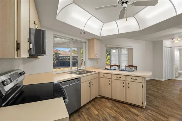a kitchen with a sink dishwasher a stove and white cabinets with wooden floor