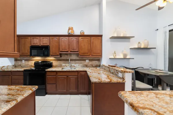 a kitchen with stainless steel appliances granite countertop a stove a sink dishwasher and a refrigerator with wooden cabinets