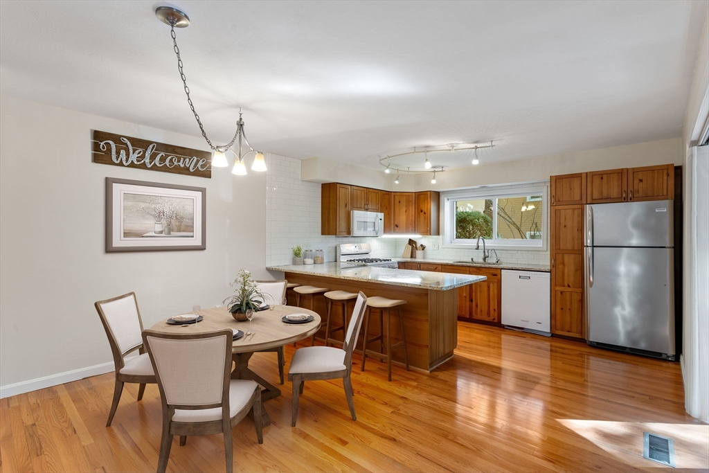 106 Captain Eames Circle, Unit 106 Ashland, MA 01721 - Photo 3 of 21 a kitchen with stainless steel appliances granite countertop a dining table chairs and wooden floor