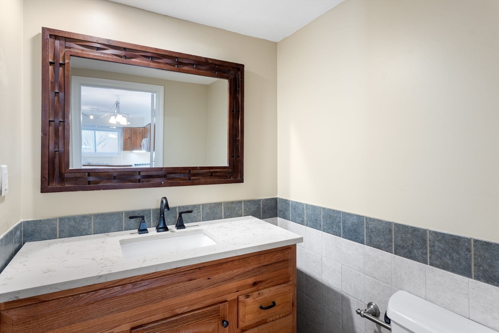 106 Captain Eames Circle, Unit 106 Ashland, MA 01721 - Photo 8 of 21 a bathroom with a granite countertop sink vanity mirror and toilet
