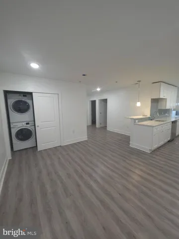 a view of kitchen and empty room with wooden floor
