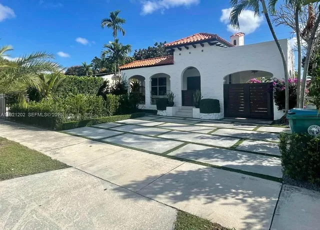 a view of a white house with a small yard and a large tree