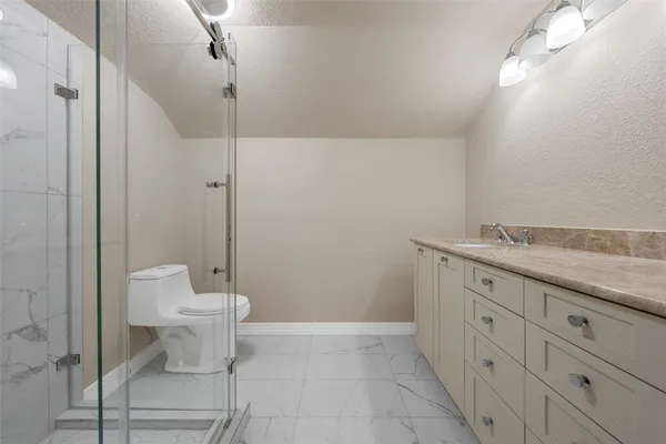 a bathroom with a granite countertop sink a toilet and a shower