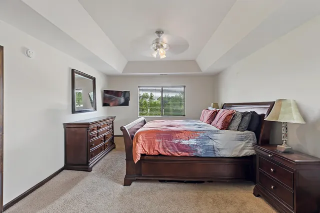 a bed sitting in a spacious bedroom next to a window and dresser