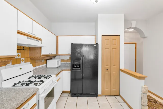a kitchen that has a refrigerator a stove and white cabinets