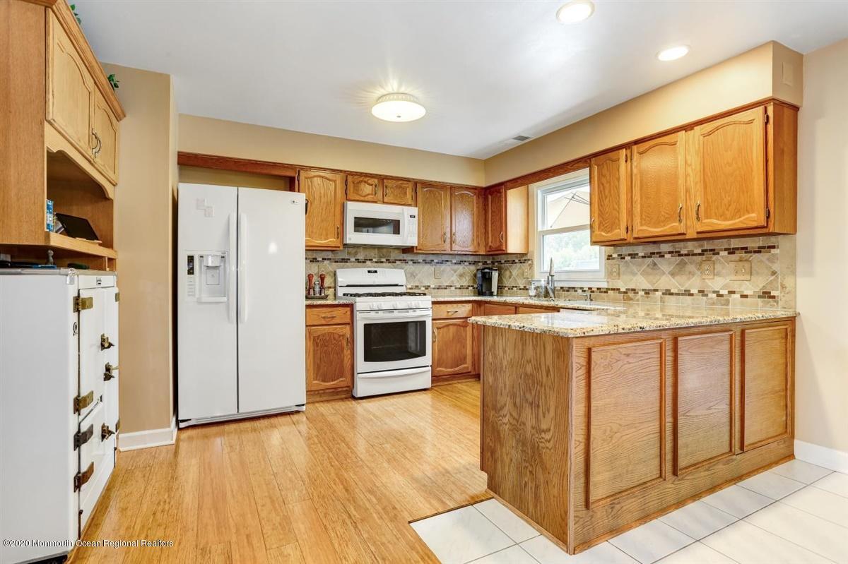 40 Hedgewood Road Howell, NJ 07731 - Photo 10 of 39 a kitchen with stainless steel appliances granite countertop a stove a sink a refrigerator with grey cabinets and wooden floor