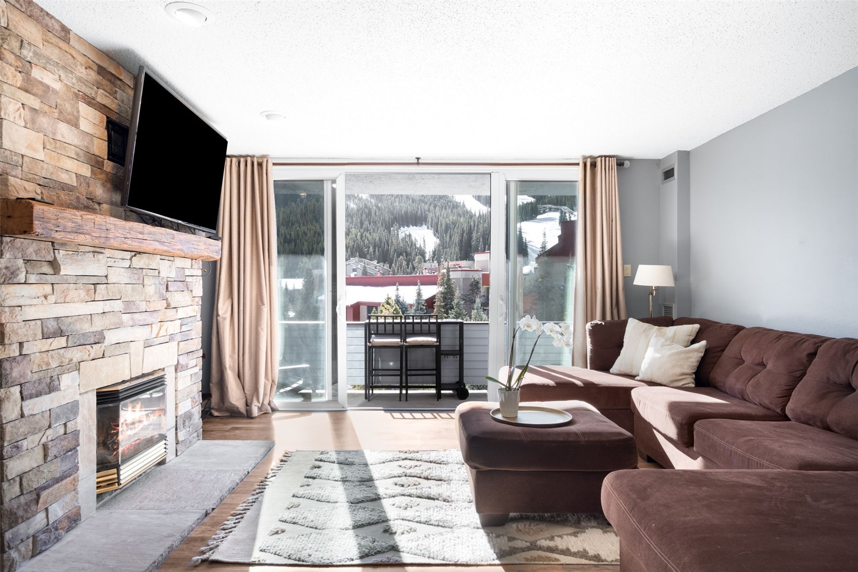 760 Copper Road, Unit F204 Copper Mountain, CO 80443 - Photo 3 of 32 Living room featuring a stone fireplace, a textured ceiling, and wood finished floors