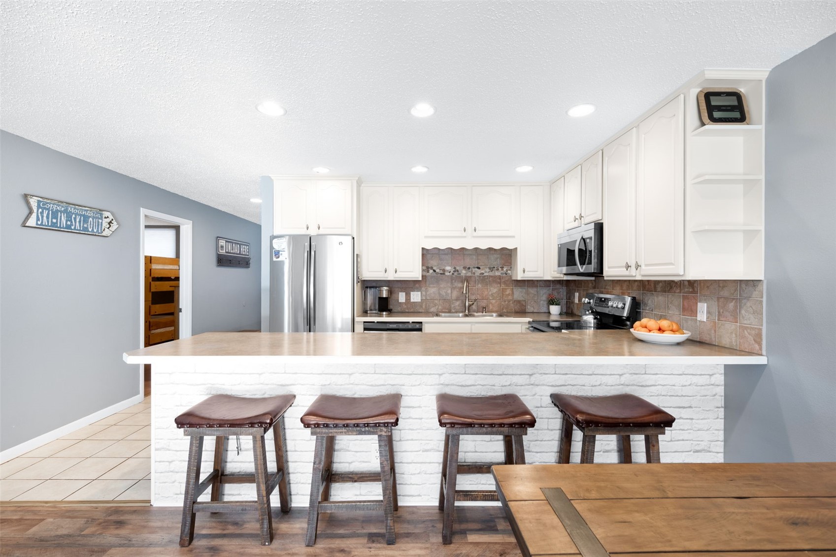 760 Copper Road, Unit F204 Copper Mountain, CO 80443 - Photo 6 of 32 Kitchen with a kitchen bar, open shelves, white cabinetry, light countertops, and a textured ceiling