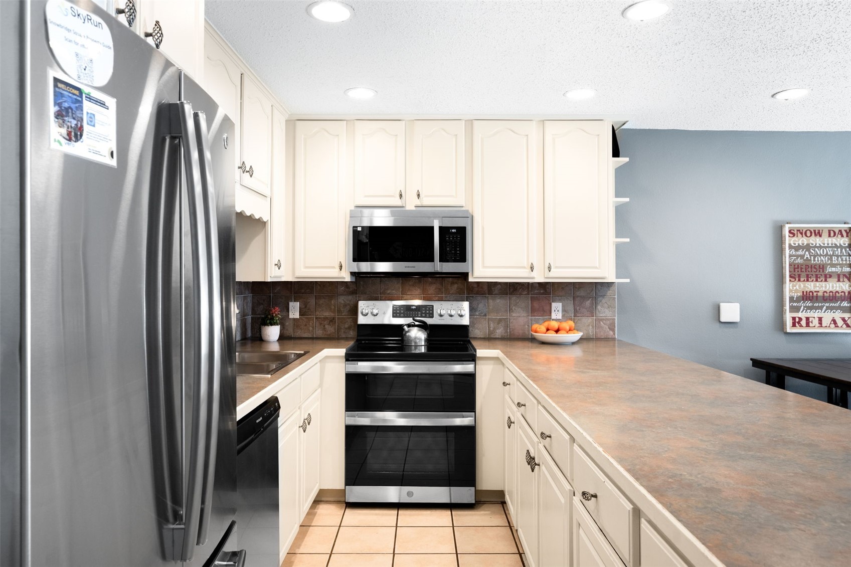 760 Copper Road, Unit F204 Copper Mountain, CO 80443 - Photo 7 of 32 Kitchen with appliances with stainless steel finishes, open shelves, a textured ceiling, decorative backsplash, and light tile patterned floors