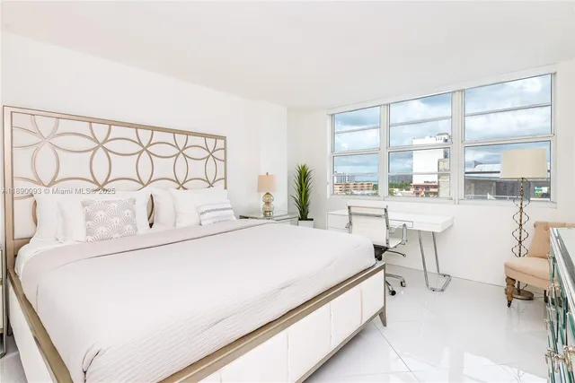 a bedroom with a bed a table and with large window