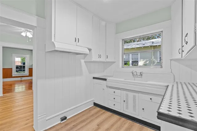 a kitchen with white cabinets sink and dishwasher with wooden floor