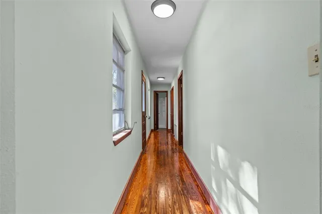 a view of a hallway with wooden floor and a bathroom