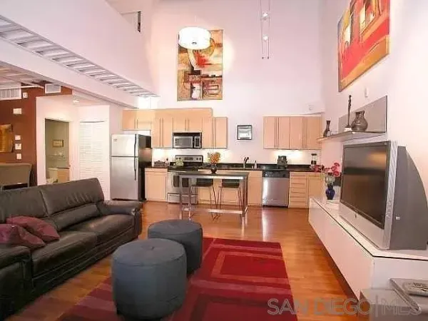 a living room with stainless steel appliances furniture and a kitchen view