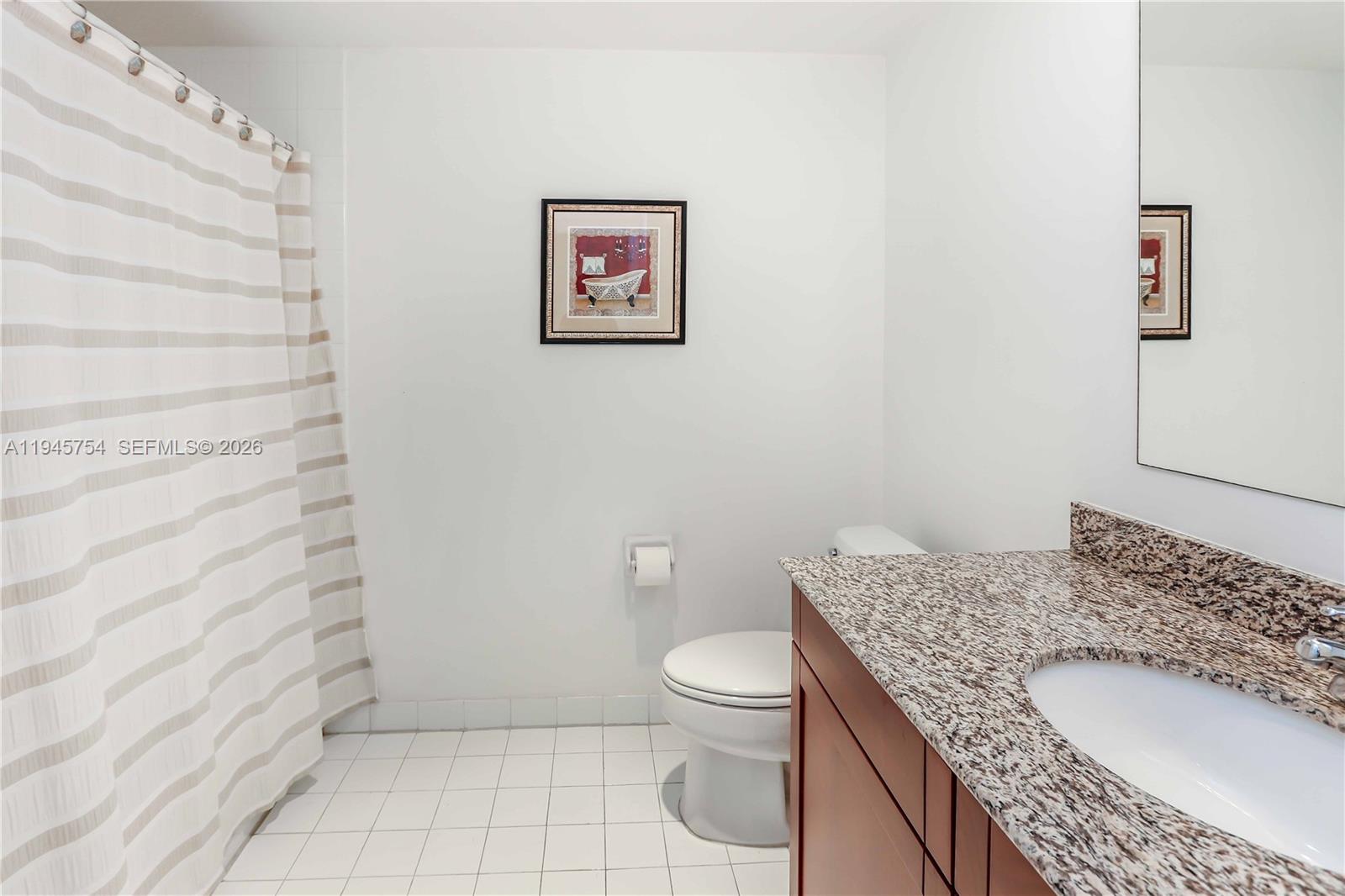 7275 Southwest 89th Street, Unit B416 Miami, FL 33156 - Photo 21 of 32 a bathroom with a granite countertop sink a toilet and a mirror