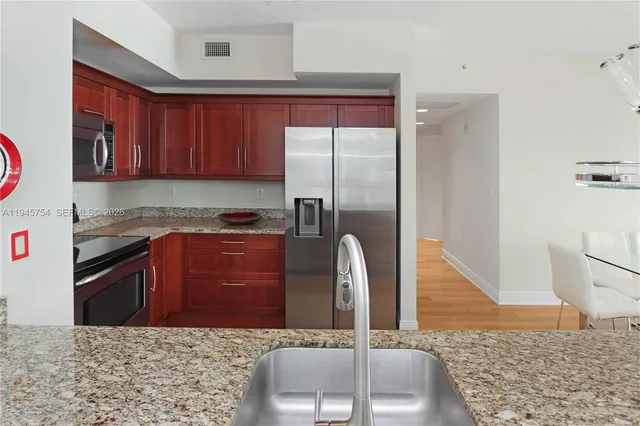 a kitchen with stainless steel appliances granite countertop a refrigerator and a sink