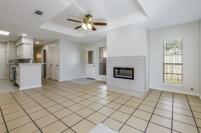 a view of a livingroom with a fireplace a ceiling fan and windows