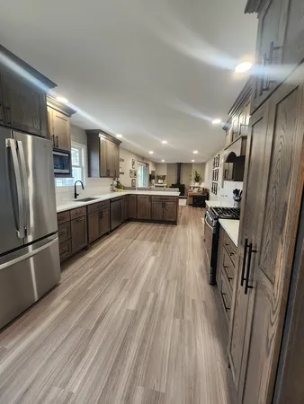 a kitchen with stainless steel appliances granite countertop a refrigerator a sink dishwasher a stove and white countertops with wooden floor