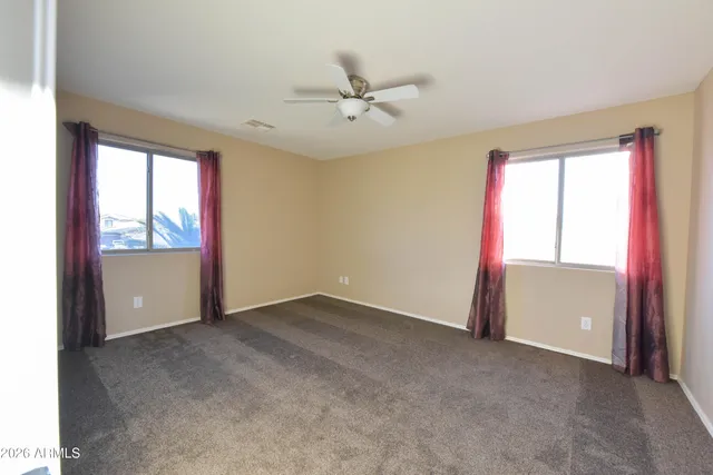 an empty room with windows and ceiling fan