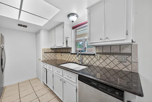 a kitchen with granite countertop a sink and a white cabinets