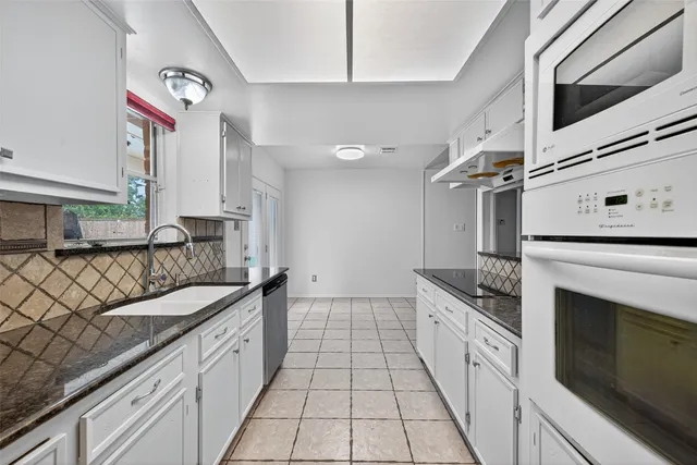 a kitchen with granite countertop a sink stove and cabinets