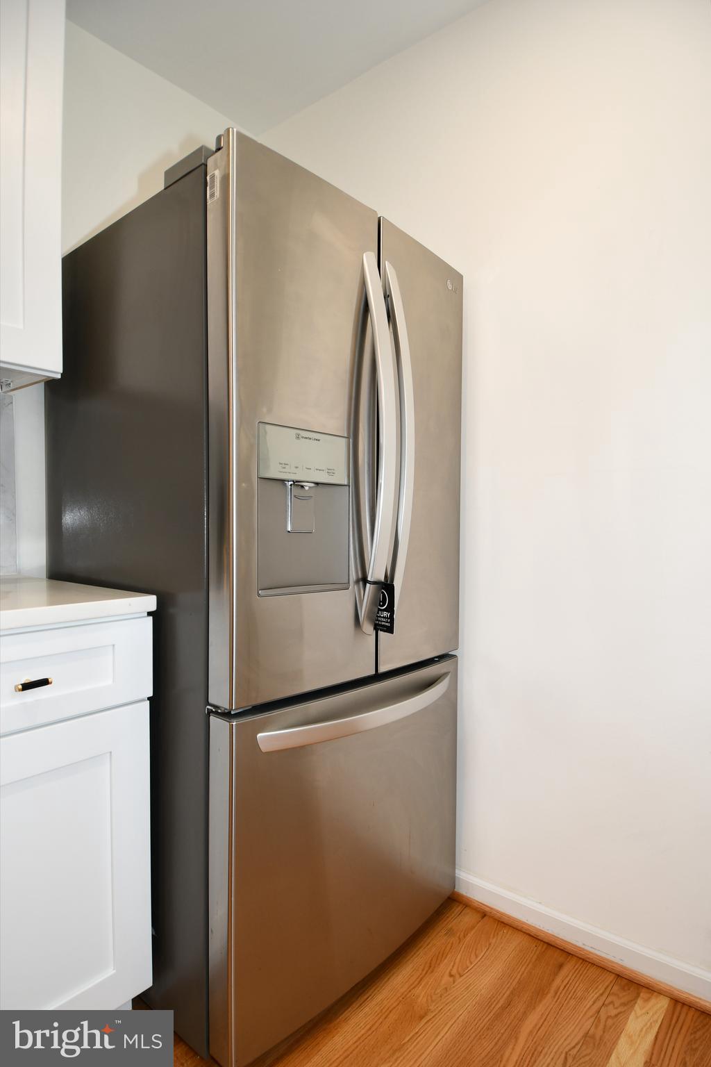 26904 Overlook Street Damascus, MD 20872 - Photo 16 of 54 a view of a refrigerator in kitchen and an empty room with wooden floor